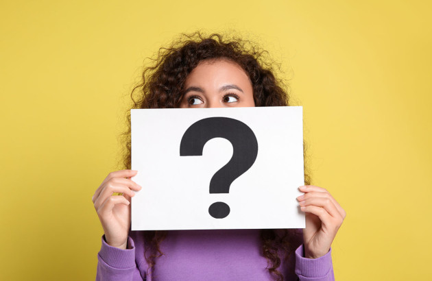Femme qui tient une feuille avec un grand point d'interrogation devant son visage