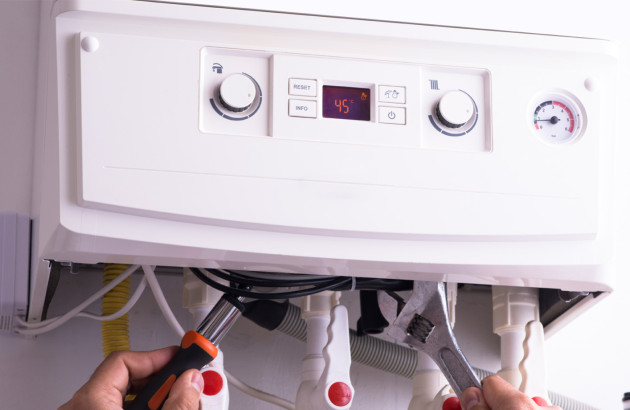 Personne qui intervient avec des outils sur une chaudière gaz