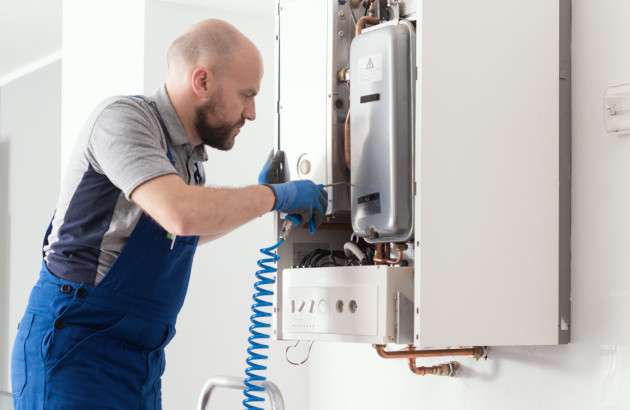 Technicien qui intervient sur une chaudière murale gaz pour y effectuer des réparations