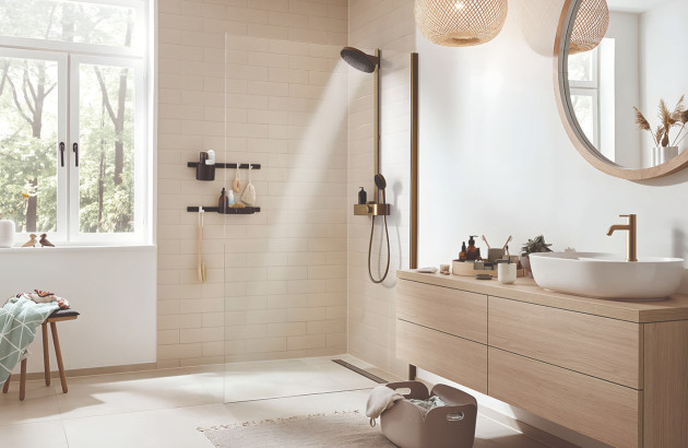 Salle de bains lumineuse avec douche ouverte, meuble vasque en bois et robinetterie finition dorée.