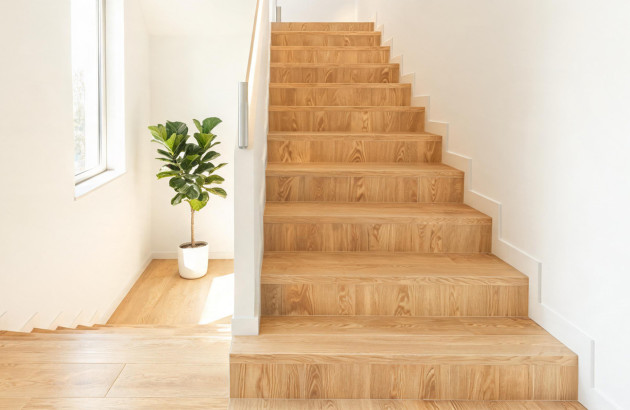 Escalier intérieur habillé d’un carrelage imitation bois clair dans une maison moderne et lumineuse.