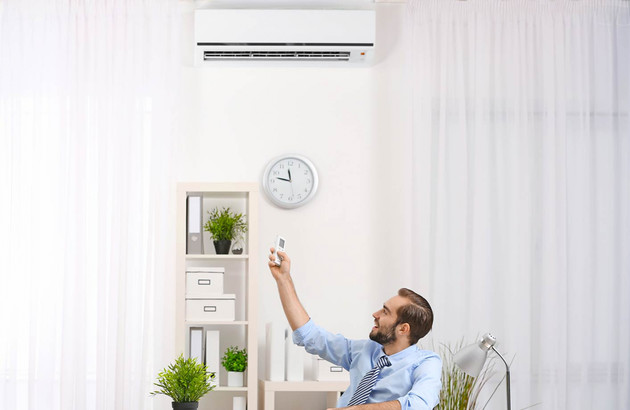 Jeune homme qui utilise une télécommande pour régler son climatiseur