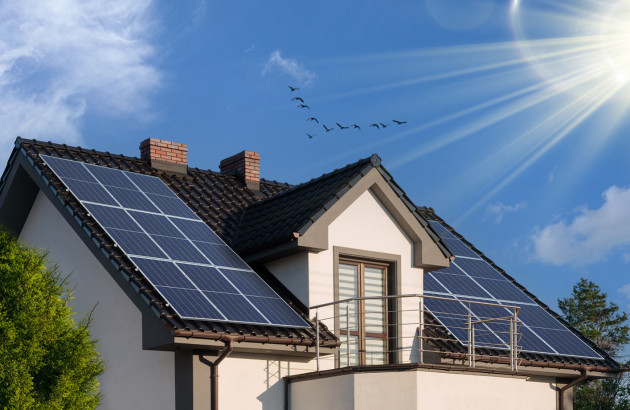 Maison équipée de panneaux photovoltaïques exposés au soleil sur plusieurs pans de toiture.