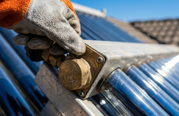Personne avec des gants qui touche une pièce de panneau solaire thermique