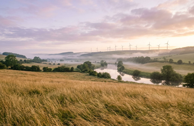Paysage rural avec éoliennes et vallée embrumée illustrant les énergies renouvelables