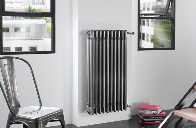 Radiateur tubulaire chromé installé entre deux fenêtres dans un intérieur contemporain.