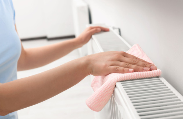 Femme qui passe le chiffon sur un radiateur pour enlever la poussière
