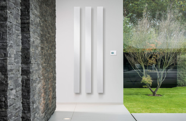 Radiateur vertical en 3 colonnes posé sur un mur de maison