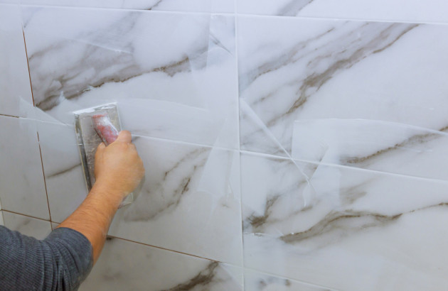 personne qui réalise des joints de carrelage mural