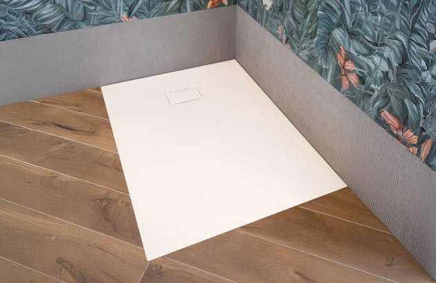 Receveur de douche extra-plat blanc installé dans une salle de bains élégante avec papier peint végétal et parquet chaleureux.