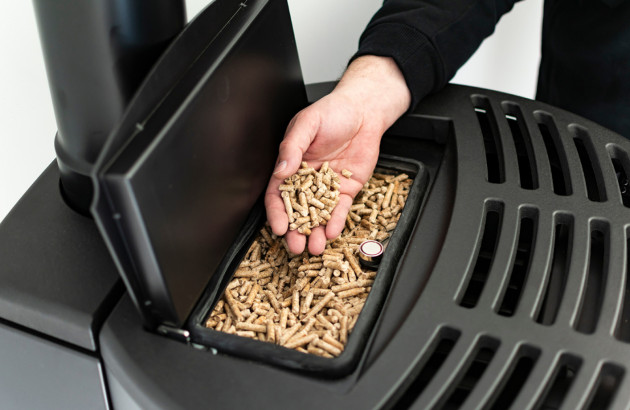 Personne qui recharge un poêle à pellets sans électricité