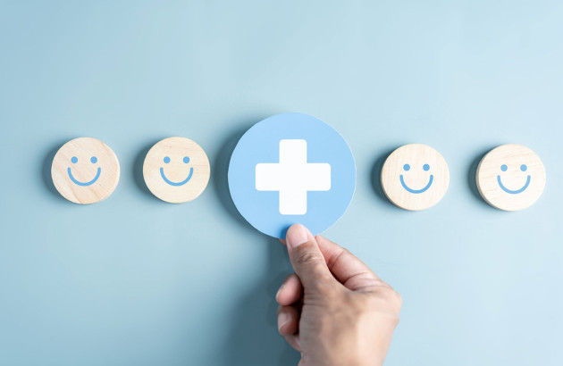  Une main tient un cercle bleu avec une croix blanche aligné avec plusieurs disques affichant des smiley