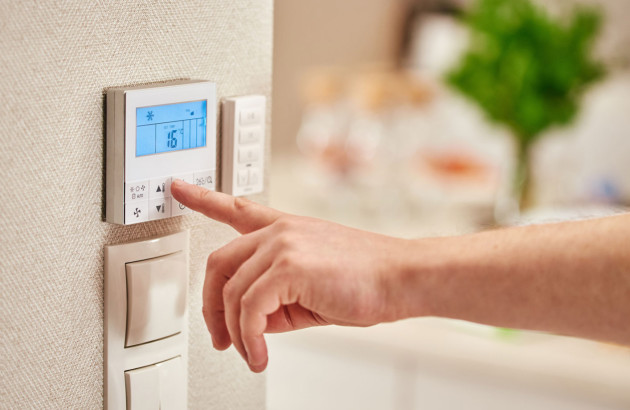Homme qui interagit avec son thermostat de chauffage intelligent