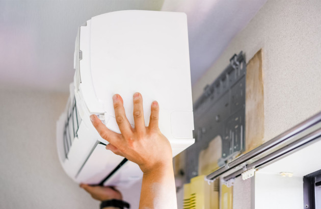 Homme qui porte une climatisation pour l'installer contre le mur