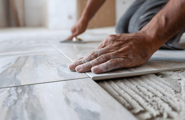 Pose de carrelage au sol : ajustement d’un carreau sur mortier-colle.