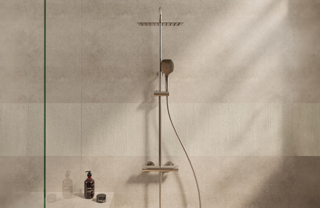 Colonne de douche avec douche de tête et douchette à main dans un espace aux tons beige naturel.