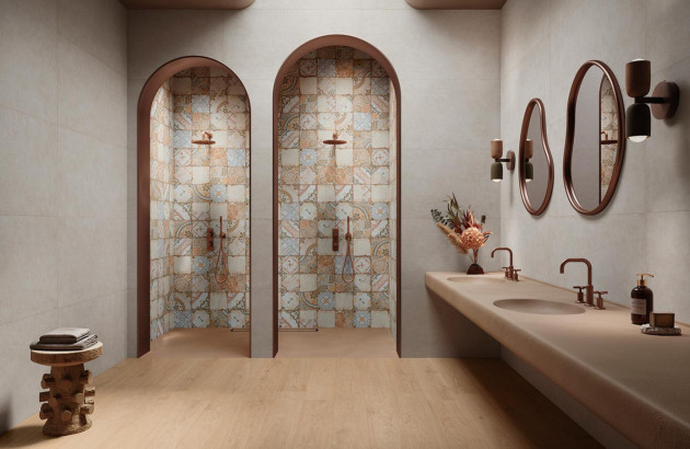 salle de bain avec deux douches en alcôve arquées ornées de carreaux à motifs et un lavabo sculpté intégré au comptoir et des miroirs dans des tons chauds et terreux