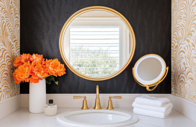 lavabo avec robinetterie dorée élégant avec un miroir et un mur d'accent noir texturé avec du papier peint doré à motifs