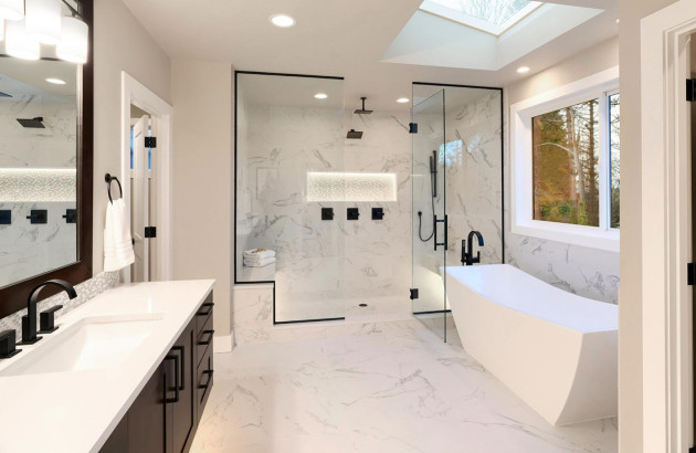 grande salle de bain avec douche et baignoire caractérisée par des murs et un carrelage en marbre blanc