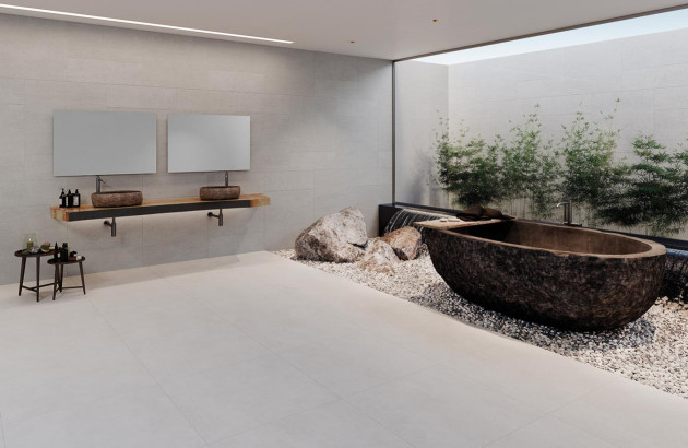 salle de bain luxueuse et zen avec une baignoire d'aspect naturel entourée de galets et de roches avec une grande vitre donnant sur un jardin de bambous