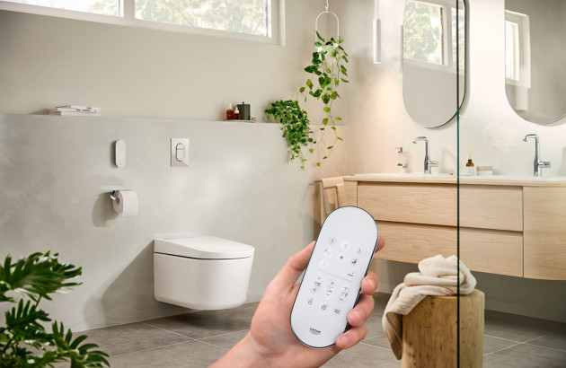 Personne qui tient une télécommande pour contrôler sa salle de bains