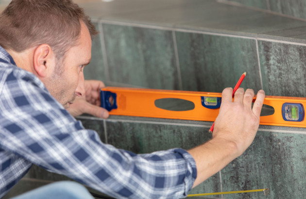 Homme qui utilise un niveau et un crayon pour tracer une ligne