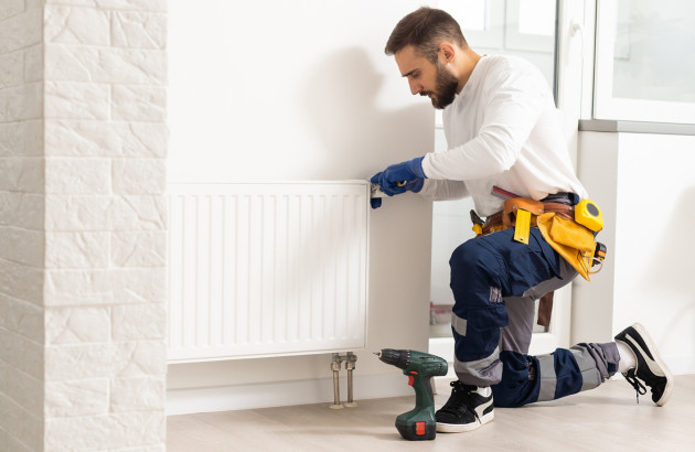 Artisan qui fixe un radiateur électrique contre un mur²