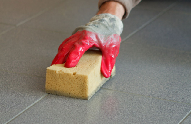 Personne avec des gants qui passe l'éponge sur son carrelage