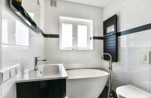 Petite salle de bains noir et blanc avec baignoire et mobilier compact