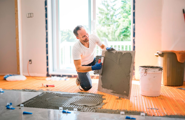 Homme qui effectue un double encollage de ses carreaux de carrelage