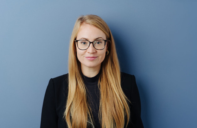 Femme avec des cheveux blonds et des lunettes qui se tient debout devant un fond bleu