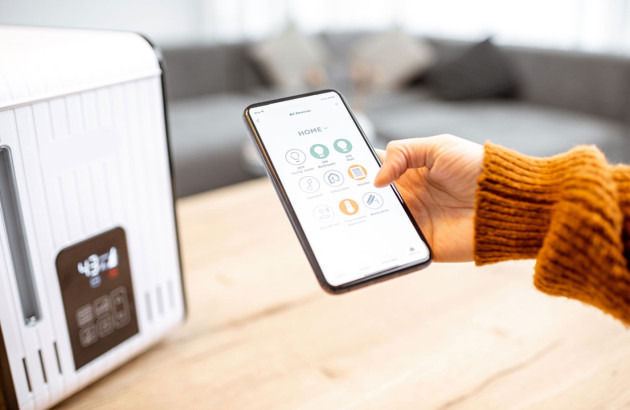 Personne qui utilise son téléphone pour contrôler un appareil connecté