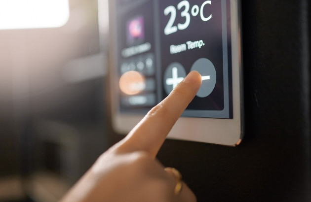 Personne qui utilise un thermostat mural domotique pour sa climatisation