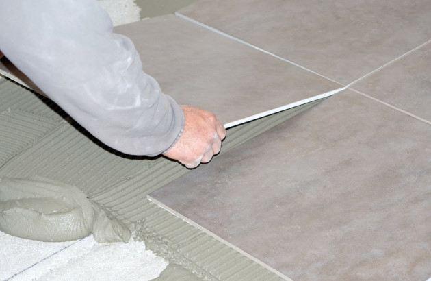 Homme qui pose des carreaux de carrelage sur du ciment