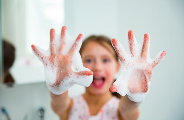 Jeune fille qui profite d'une robinetterie sans contact pour se laver les mains