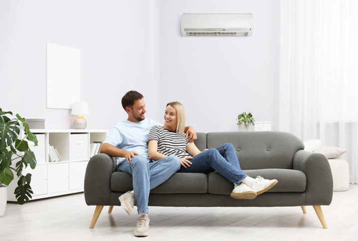 Couple installé dans un salon moderne avec climatisation réversible murale, confort thermique au quotidien