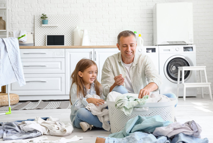 Homme et sa fille qui sont très heureux de mettre du linge dans le panier de linge