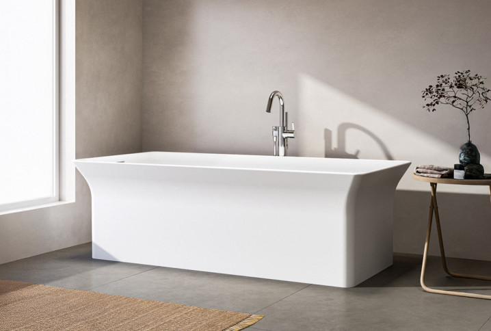 Baignoire îlot rectangulaire au design minimaliste installée dans une salle de bains contemporaine aux tons doux et naturels.