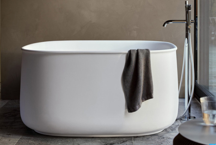 Baignoire îlot blanche aux lignes arrondies installée dans une salle de bains contemporaine.