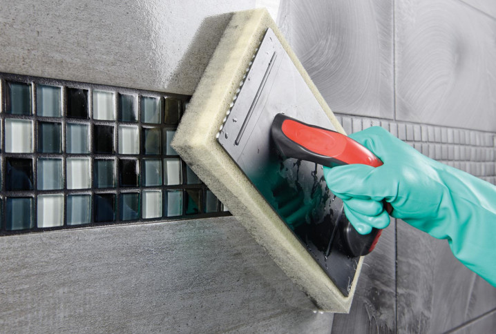 Homme qui utilise une éponge de carrelage pour enlever les résidus de colle de mosaïque murale