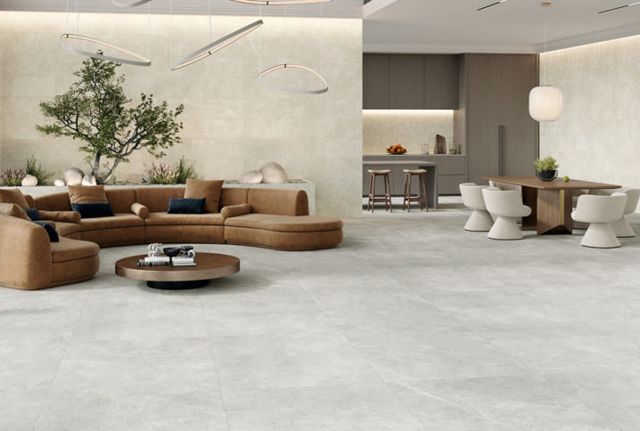 Grand salon contemporain avec carrelage effet pierre claire grand format et espace de vie ouvert chaleureux.