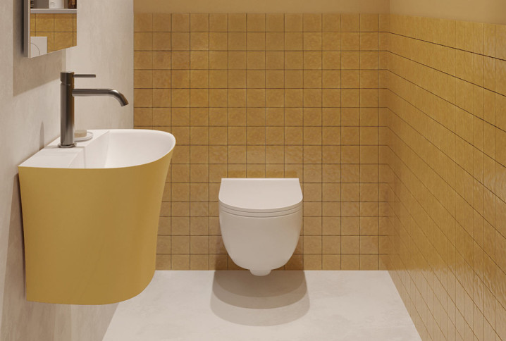 Petit espace WC avec toilette suspendue blanche, lave-mains jaune et carrelage mural ocre.
