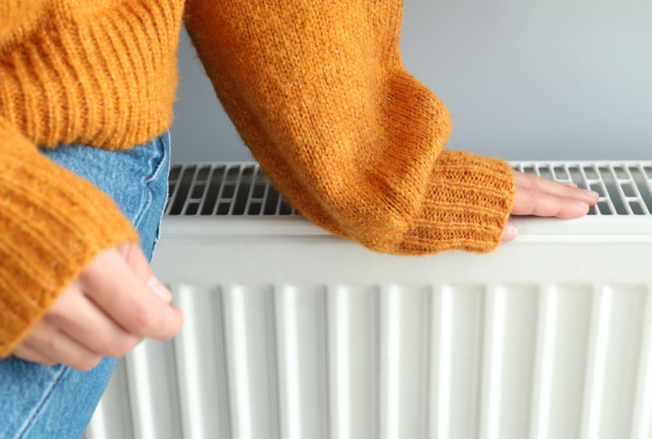Femme en pull beige qui ressent la chaleur de son chauffage