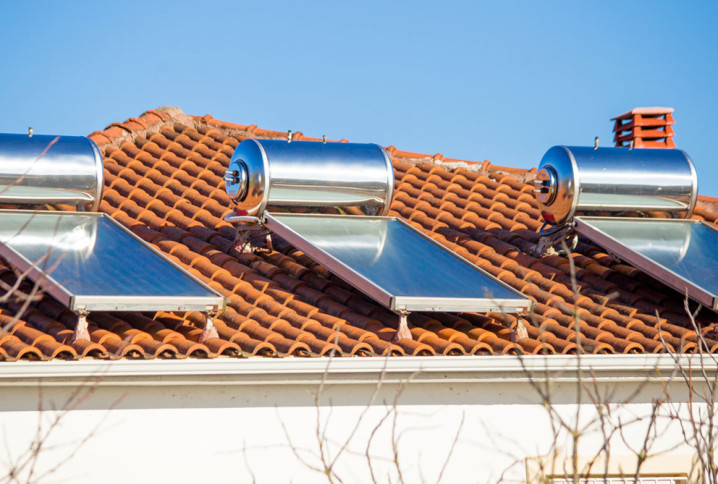 Trois panneaux solaires thermiques avec réservoir qui sont installés sur un toit de maison