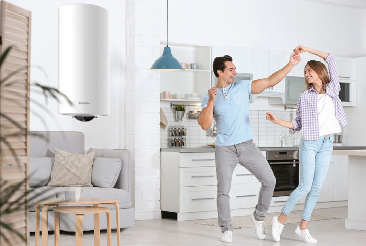 Couple qui danse dans sa cuisine avec un chauffe-eau positionné au dessus du canapé du salon