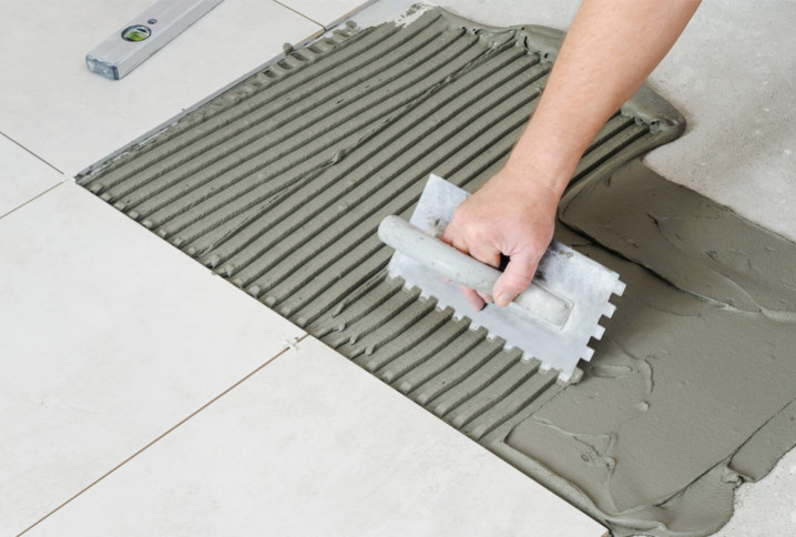 Homme qui utilise un peigne pour poser des carreaux de carrelage