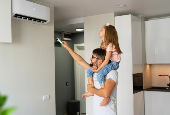 Famille réglant une climatisation murale dans un salon