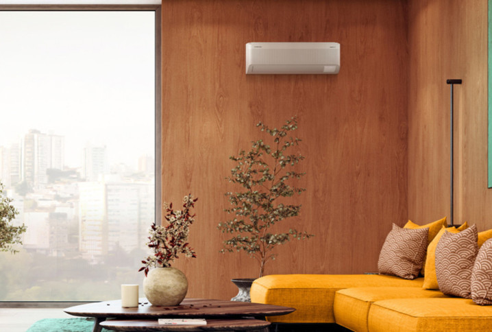 Salon moderne avec climatisation réversible murale installée sur un mur en bois au-dessus d’un canapé jaune design.