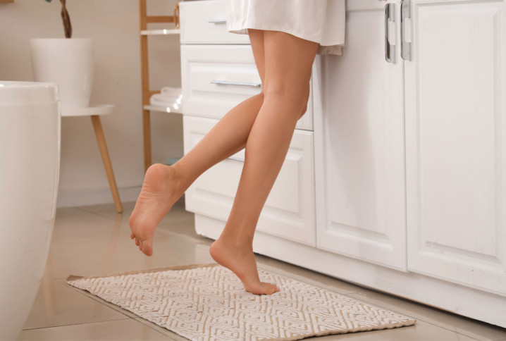 Pieds féminins sur un tapis de salle de bain