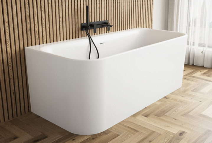 Baignoire îlot moderne adossée à un mur en tasseaux de bois avec robinetterie noire mate.